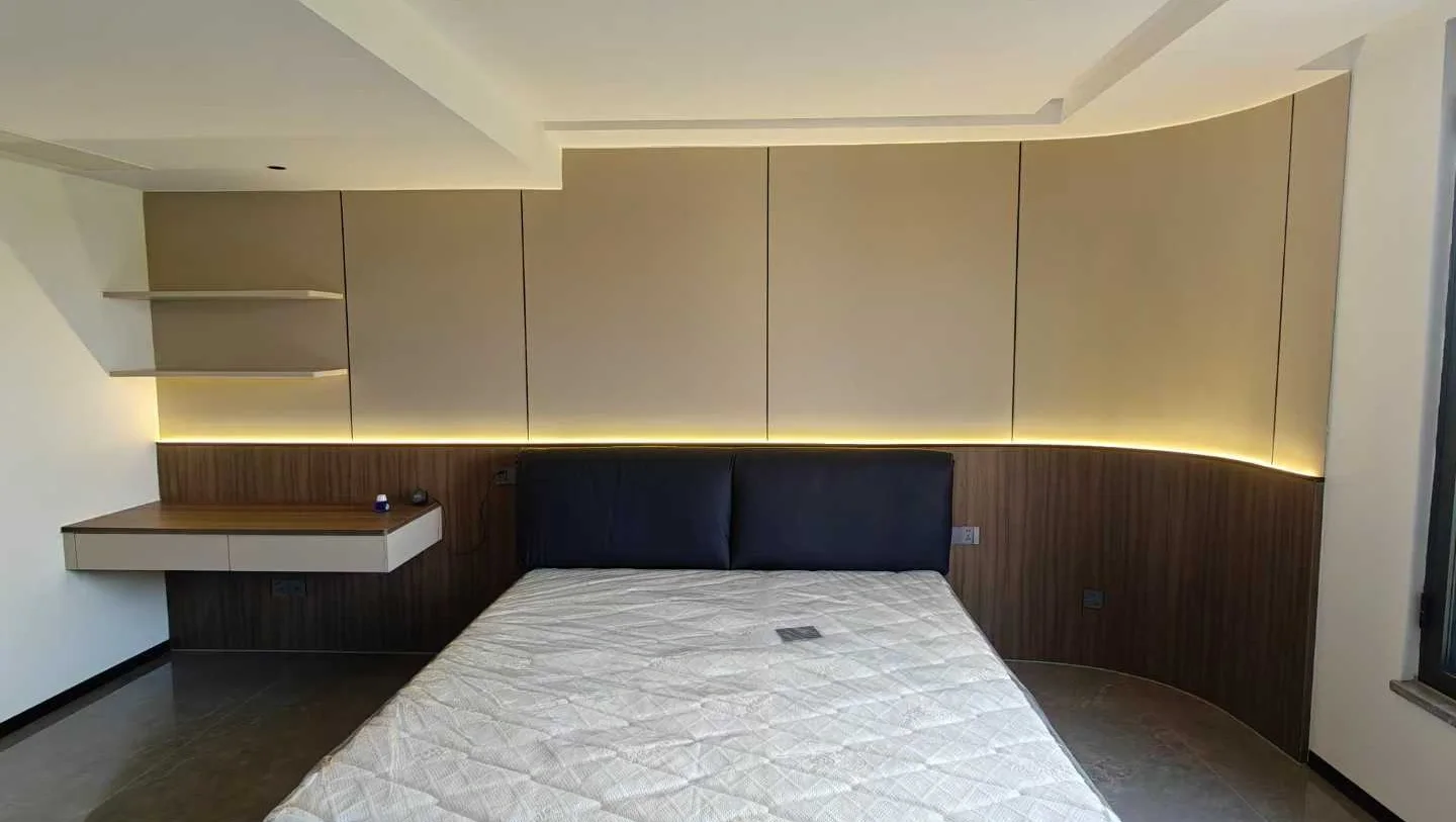 Master bedroom with curved upholstered headboard wall and wood veneer